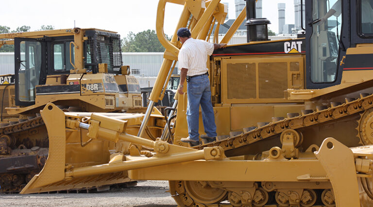 The man is checking the CAT heavy equipment.