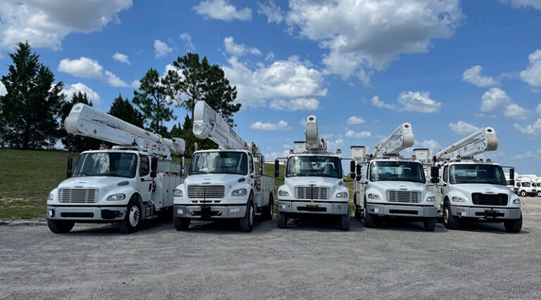 A fleet of utility trucks is parked in a lot.