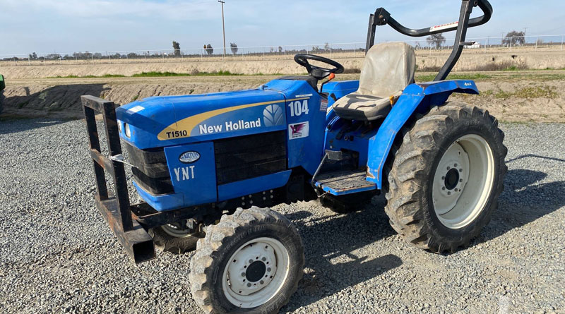 New Holland T1510 MFWD Tractor is parked in front of the empty space.