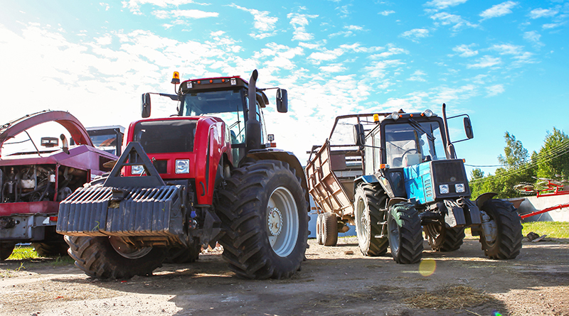 Agricultural machinery, tractors and equipment outdoors, near the garage, ready to work in the field.